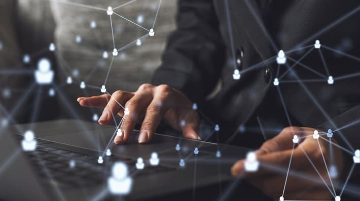graphic of connected dots overlaid on image of a person's hands on a laptop