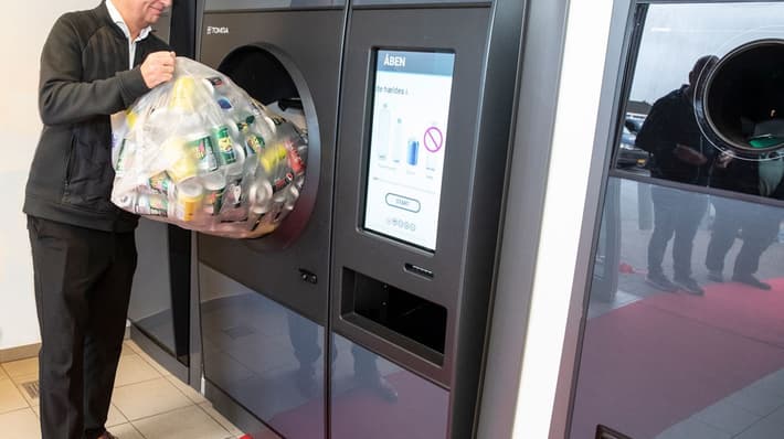 Man pouring bottles into R1 reverse vending machine