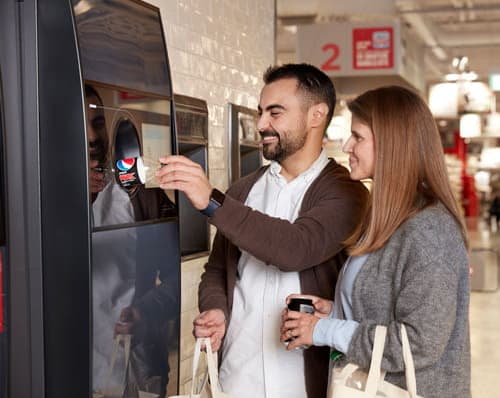 Man and woman using TOMRA Reverse Vending Machine