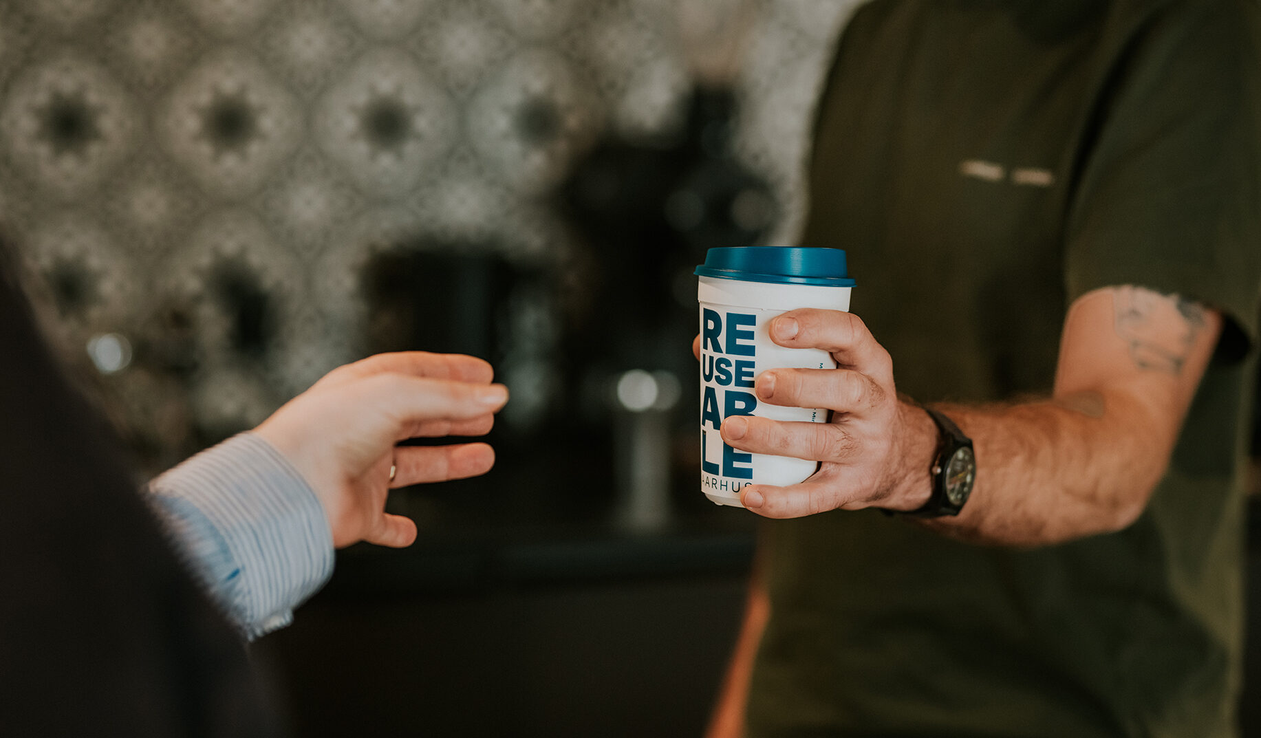 Barista serving coffee in a Reuseable cup