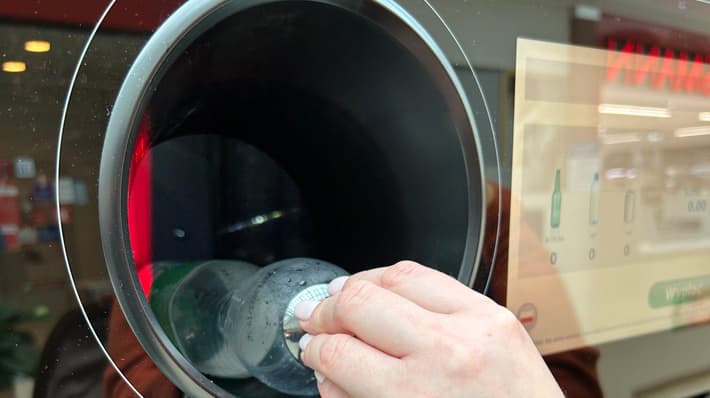Person inserting plastic bottle into a reverse vending machine