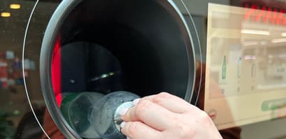 Person inserting plastic bottle into a reverse vending machine