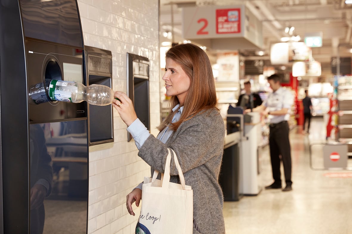 Consumer returning plastic bottle in TOMRA reverse vending machine