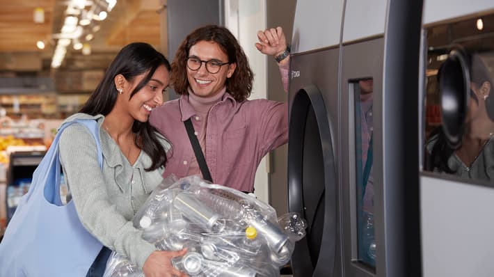 Happy consumers return their used beverage containers at a reverse vending machine