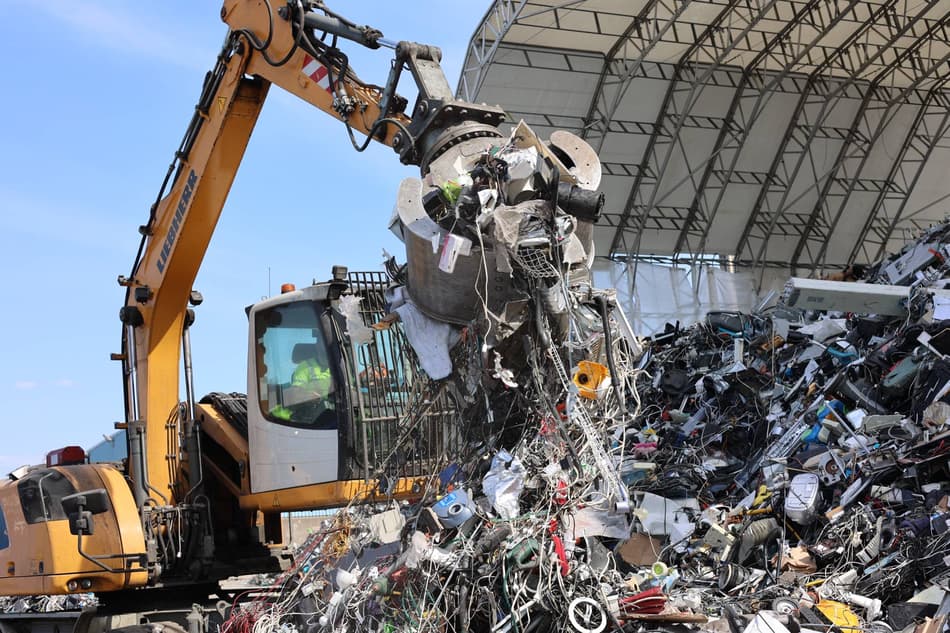 A crane moves material waste at a facility