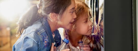 Girls looking into reverse vending machine