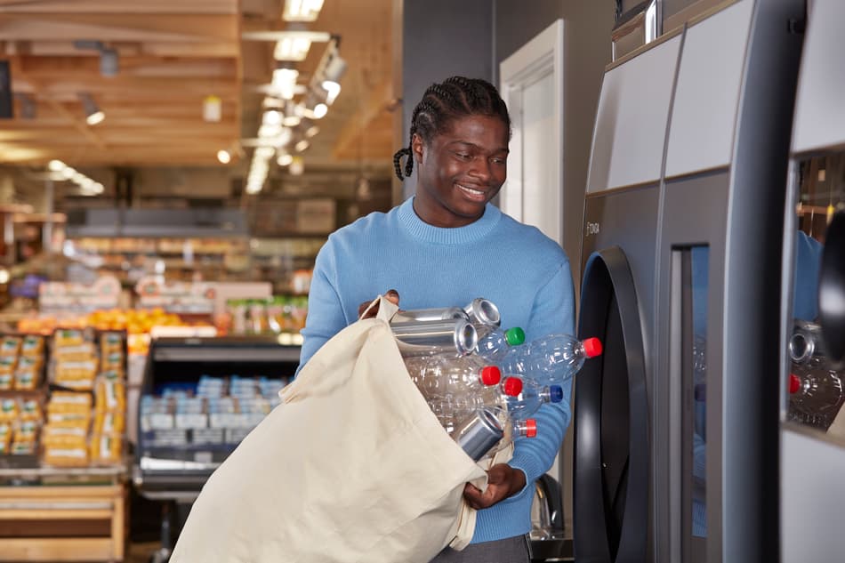 Man dropping a bag of empties into a TOMRA R1 reverse vending machine