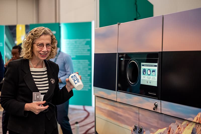Inger Andersen, UNEP Executive Director, testing the return of a reusable cup at a TOMRA Reuse machine during INC-4 in Ottawa.