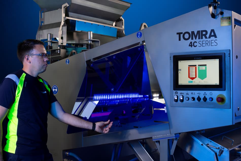 A man lifts the folding door on the TOMRA 4C optical sorting machine