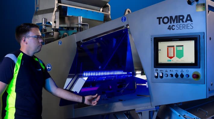 A man lifts the folding door on the TOMRA 4C optical sorting machine