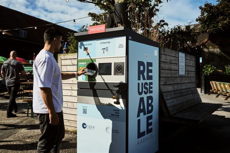 Mann gibt Mehrwegbecher in TOMRA Reuse-Automat zurück
