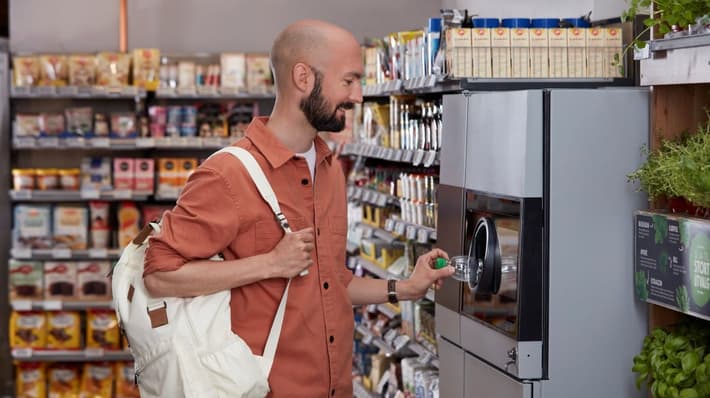 Slika čoveka koji vraća limenke u reciklažni automat