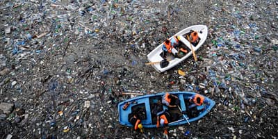 Boat floating in an ocean full of litter