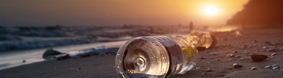 plastic pollution washed up on a beach with setting sun