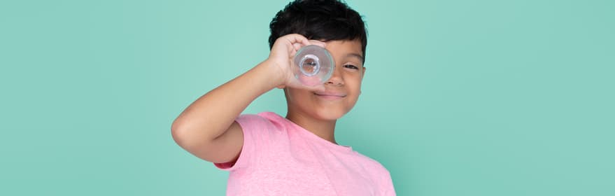 Smiling boy using a bottle as a telescope