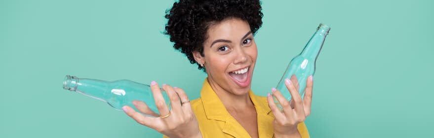 Smiling woman holding up two glass bottles 