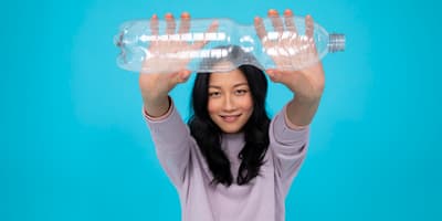 Asian girl holding one PET bottle and smiling