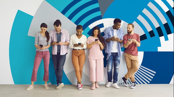 People standing in a row using their mobile phones against a wall showing the TOMRA Orbit graphic