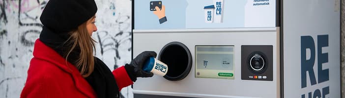 Woman returning a REUSABLE cup at a collection machine in Aarhus Denmark