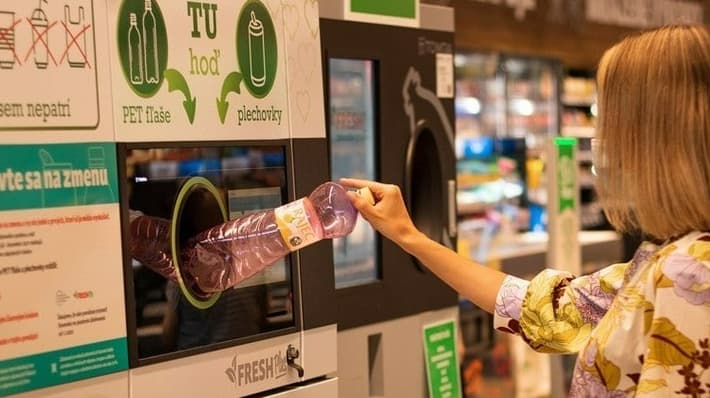 Woman feeding bottles in the reverse vending machine