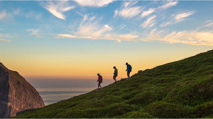 Three people walking on mountain ridge