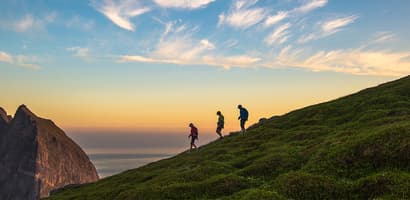 Three people walking on mountain ridge