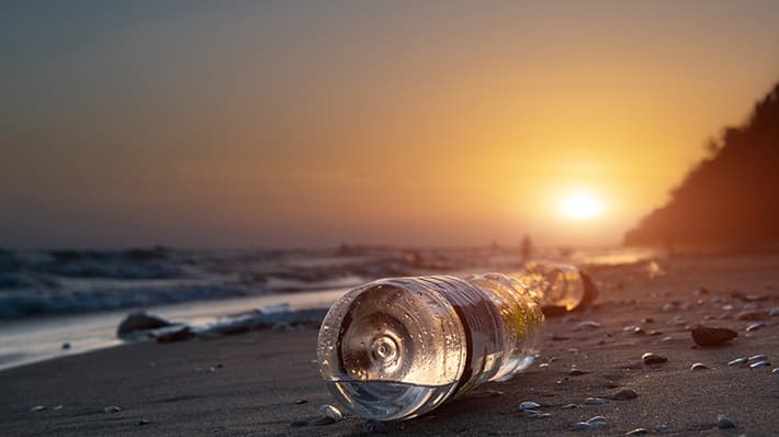 plastic bottles washed up on beach with setting sun
