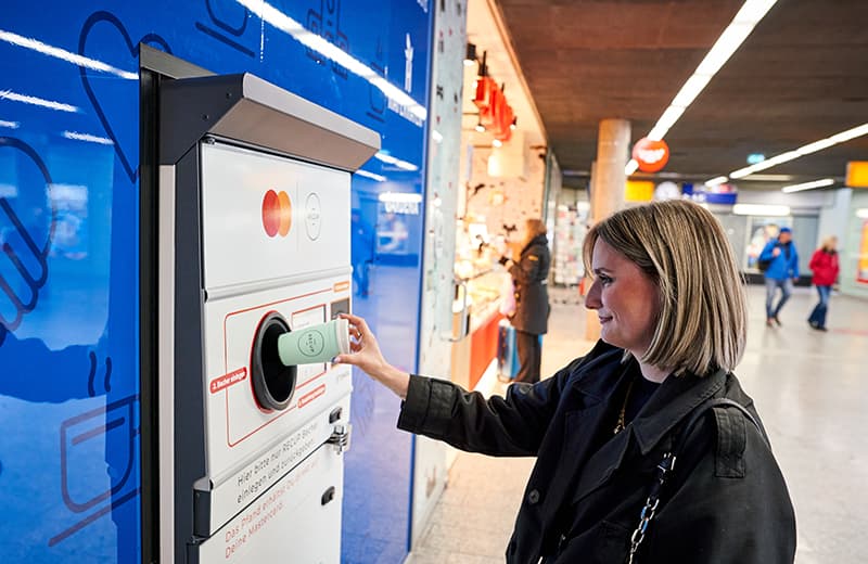 Woman returning a RECUP reusable cup at TOMRA return station at Freiburg central train station in Germany