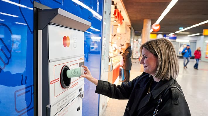 Woman returning a RECUP reusable cup at TOMRA return station at Freiburg central train station in Germany