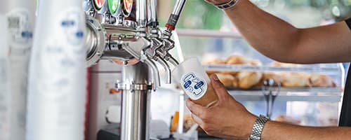 draft beer being poured into a reusable cup