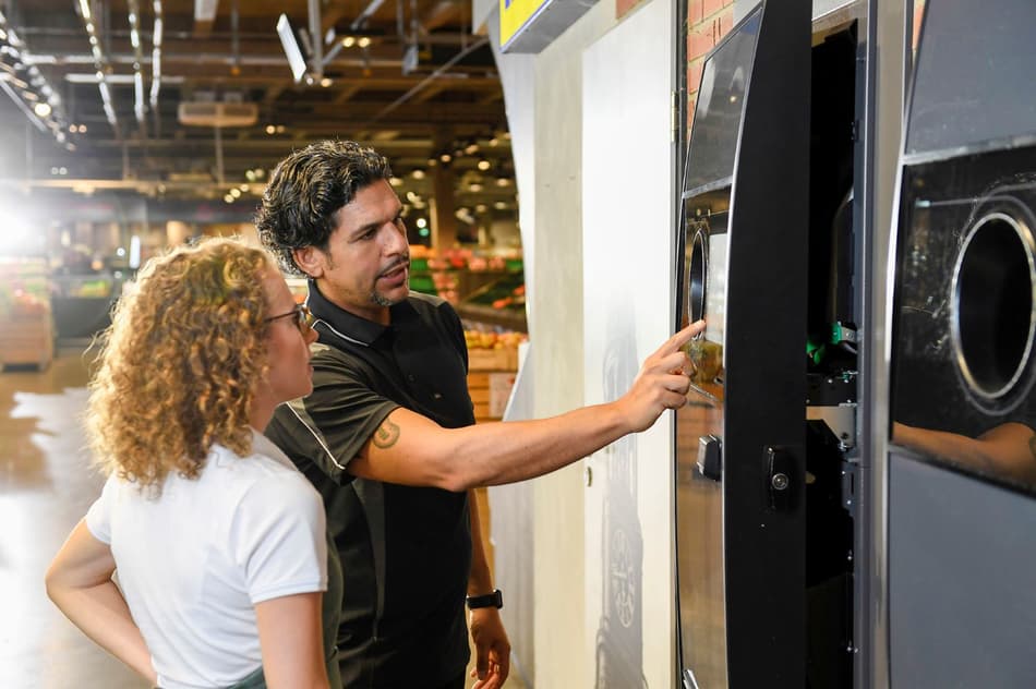 Retailer and TOMRA service technician with reverse vending machine