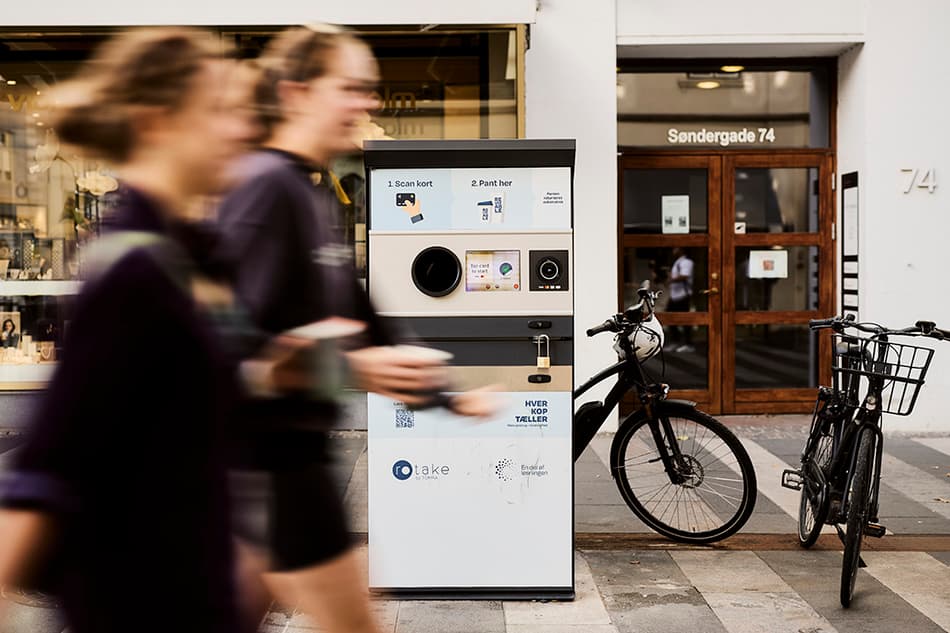 Two women running by a REUSEABLE collection machine in Aarhus city center.
