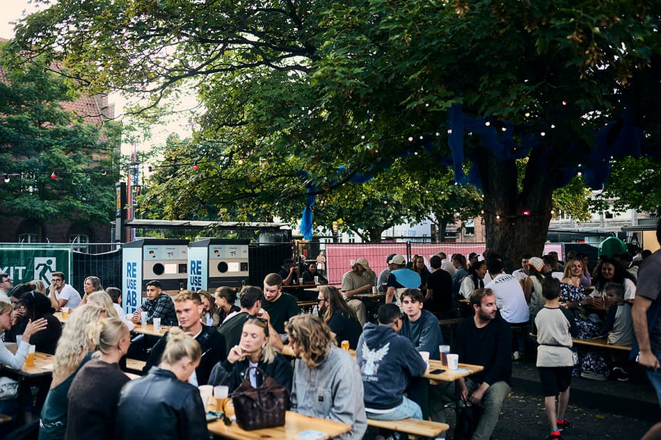 people sitting at picnic benches with drinks in REUSEABLE cups during Aarhus Festuge