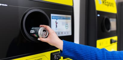 Ręka z puszką na tle recyklomatu