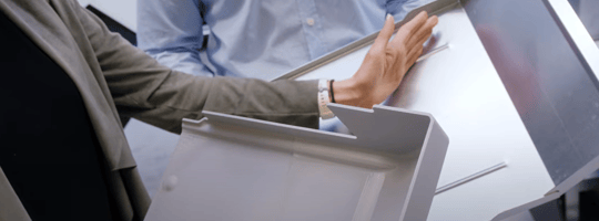 Two people holding and choosing material types for TOMRA R2 reverse vending machine